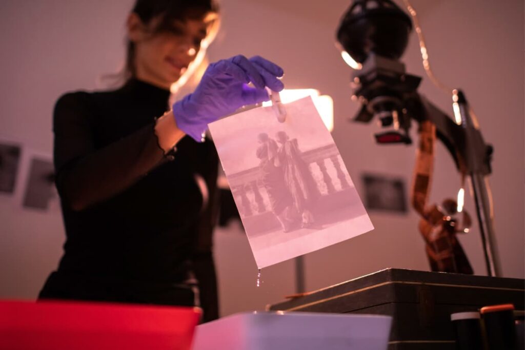 A woman who is wearing Surgical gloves developing film through film developing machine at Walmart.