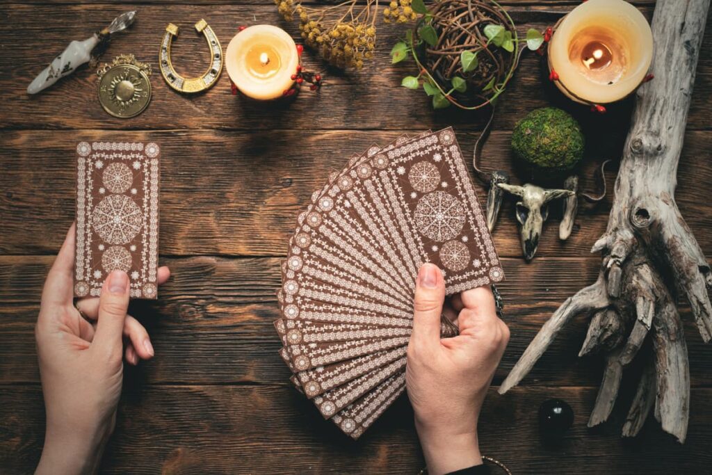 A set of 16 Walmart Pokemon cards holding a person on a table consists of two candles, dried flowers, bunch of leaves, metal ornaments and a tree wood.