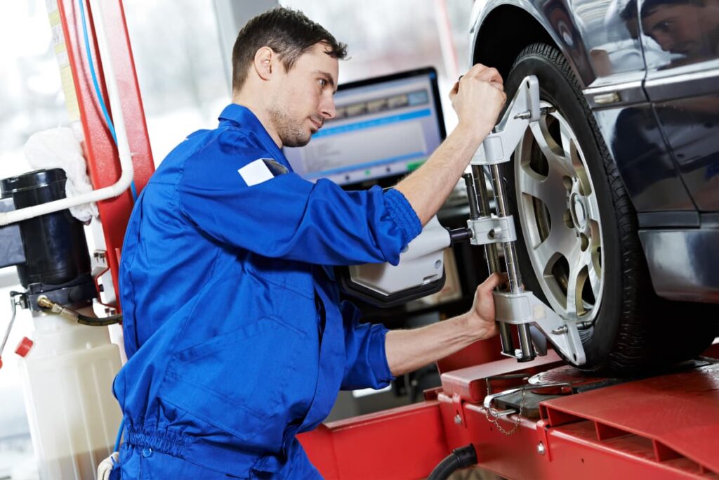 A man wearing blue color dress ad doing wheel alignment to car at Walmart Auto Care Center.