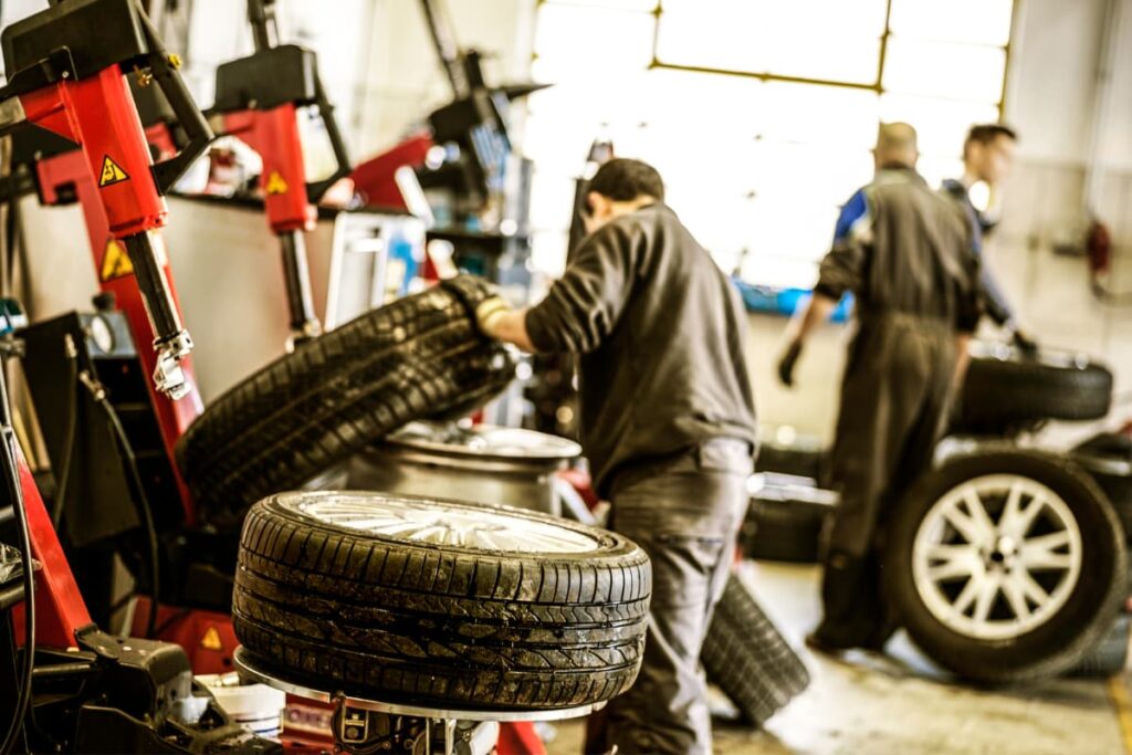 Three persons repairing and checking six wheels of different vehicles at Walmart Auto Center.