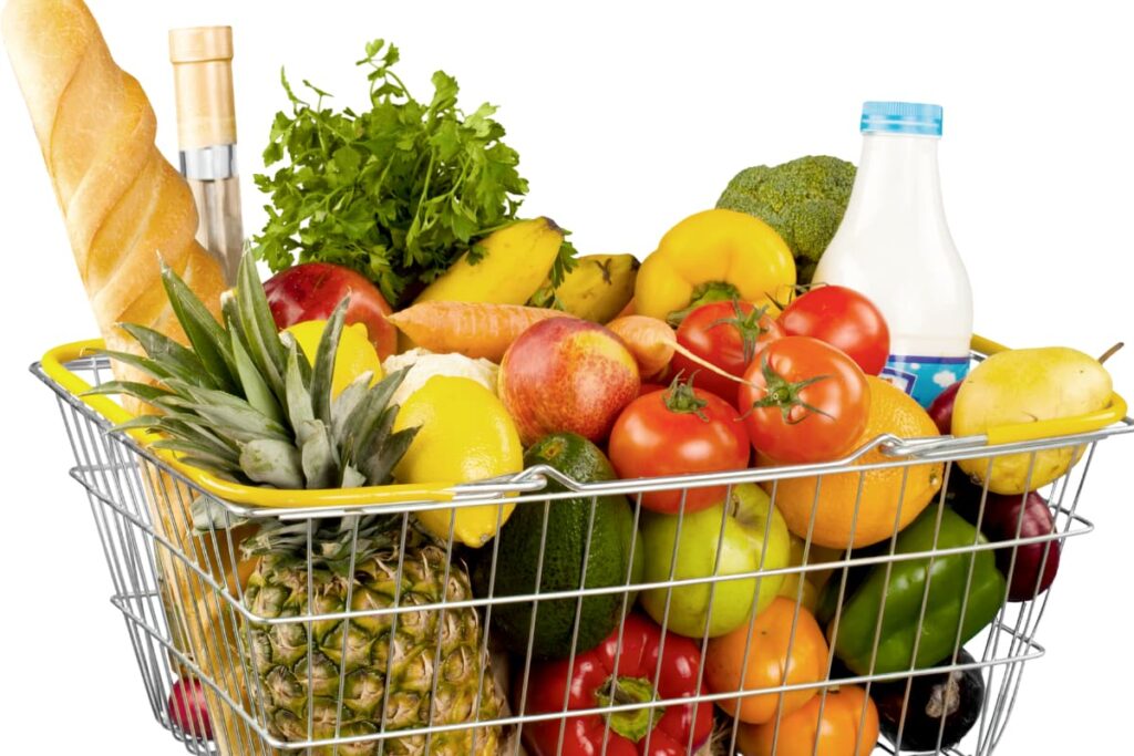 Walmart Deliver Groceries like tomatoes, milk, capsicum, carrots, banana, pine apple, red bell peppers, yellow bell peppers, coriander leaves, avocado, lemons, peer in a basket.