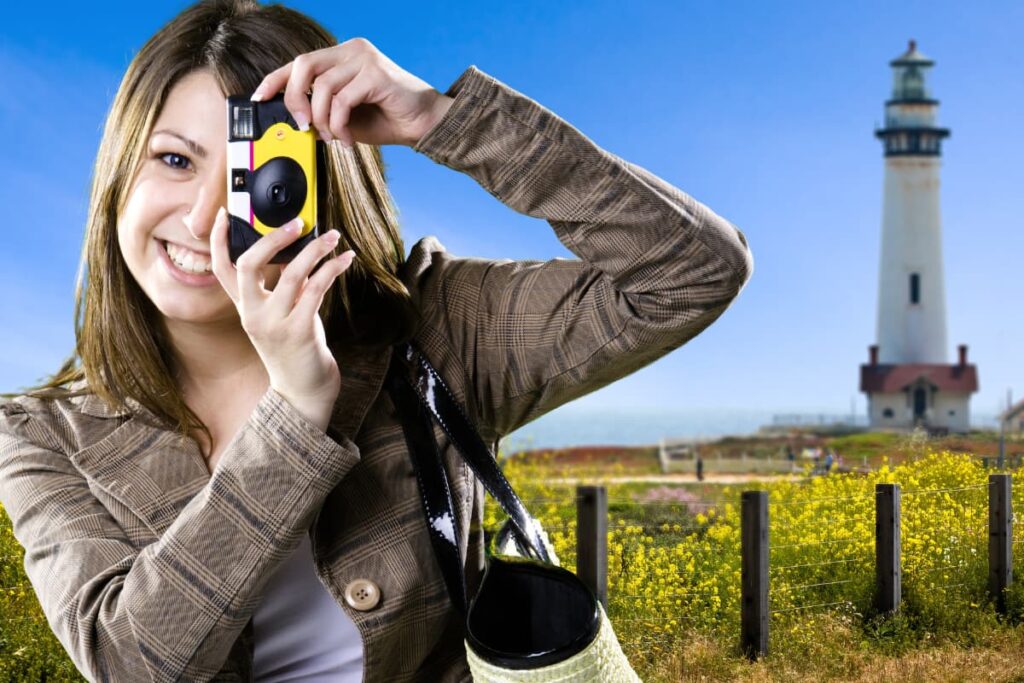 A women taking pictures with Walmart Disposable Camera with a view of Canola and a light house. 