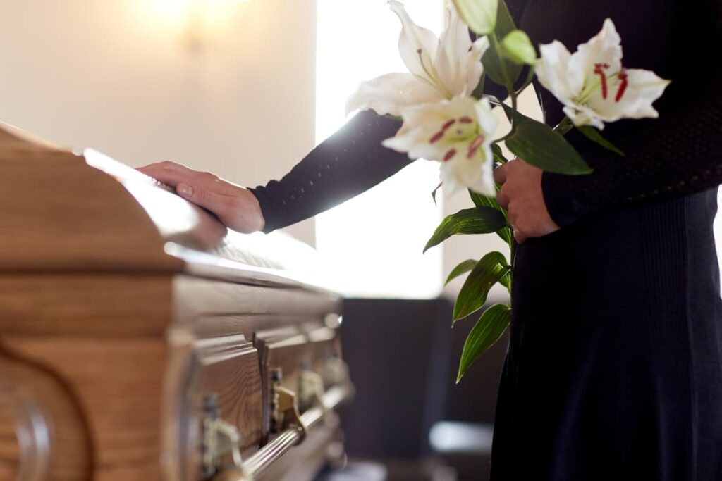 Walmart Casket in front of the church standing by a person holding with white flowers.