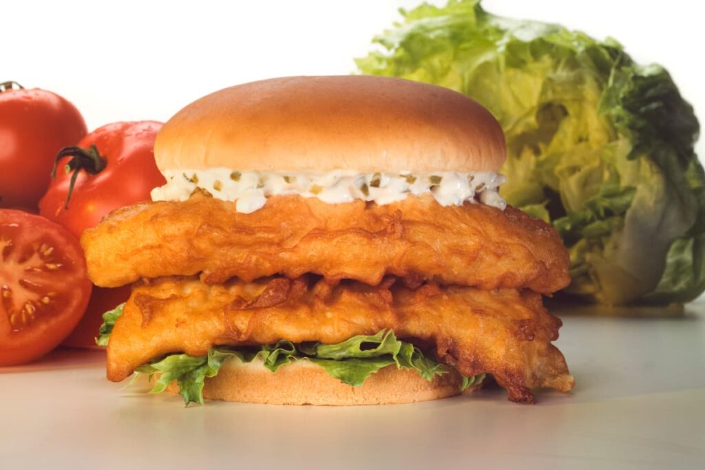 Burger King Fish Sandwich contains 2 fish slices, 2 bread slices, lettuce, and mayonnaise. Besides Fish Sandwich there are 2 tomatoes and one sliced tomato along with the lettuce.
