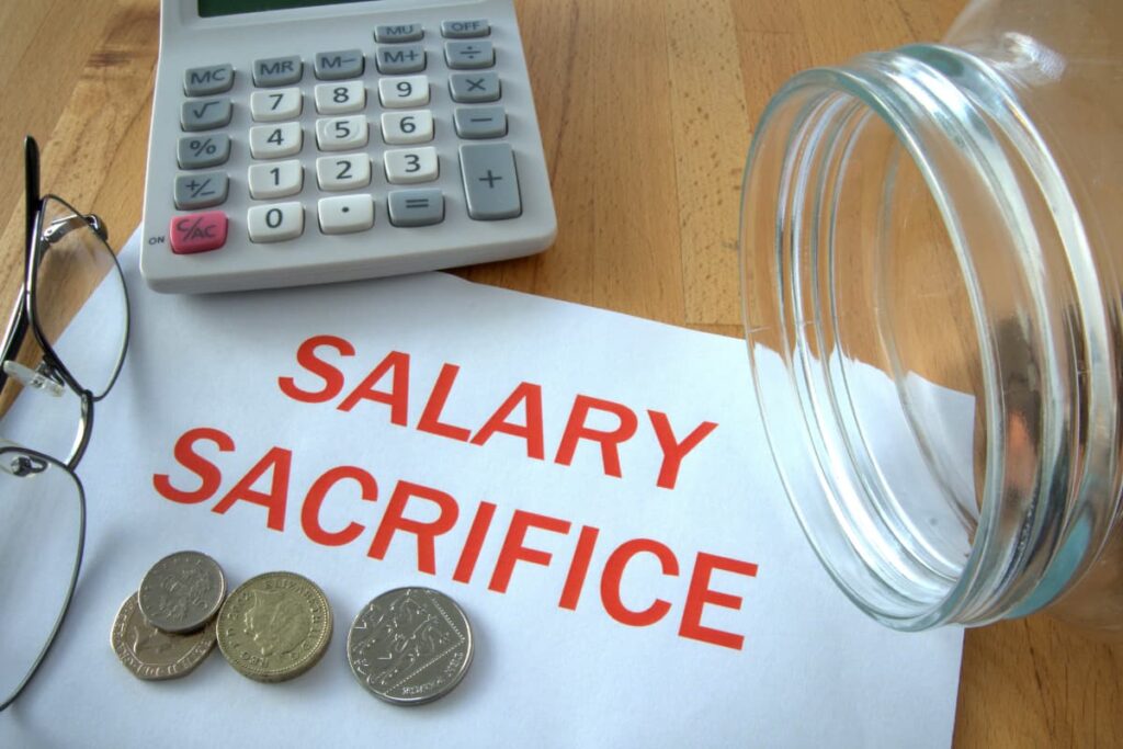 Starbucks salaries depends on their job position. In a table there is a paper which is written salary sacrifice, and some coins on the paper. Beside there is a glass bottle, one spects, one calculator on the table.