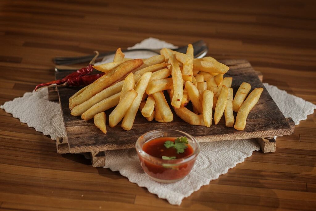 Burger King Large Fries are served in a wooden plate with the red ketchup in a small glass bowl.