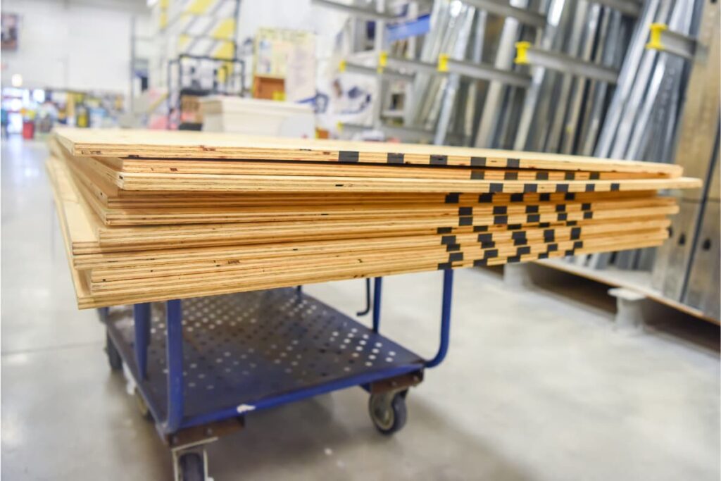 There are bulk of Lowe's Plywood's in a blue trolley.