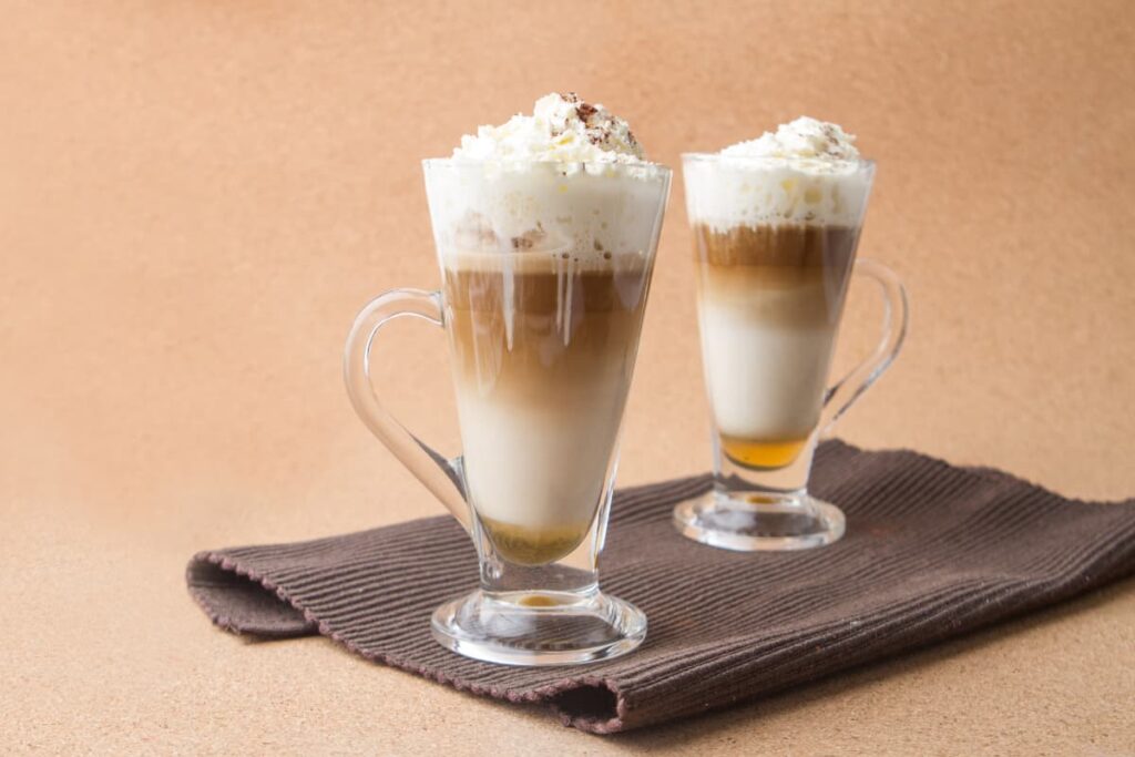 Starbucks Caramel Macchiato serves a medium size glass along with the napkin. Starbucks Caramel Macchiato is garnished with the caramel powder, and it is topped with the whipped cream and at bottom caramel, milk. 