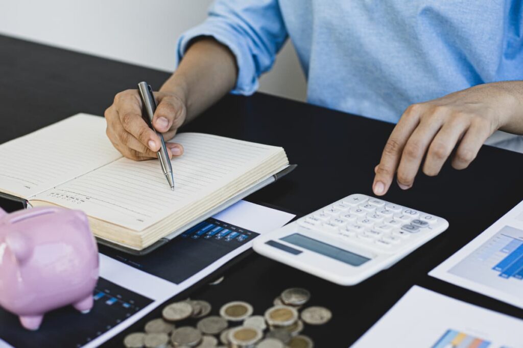 Save Money At Walmart checked by a person with the help of calculator, pen, diary ,coins and piggy bank.