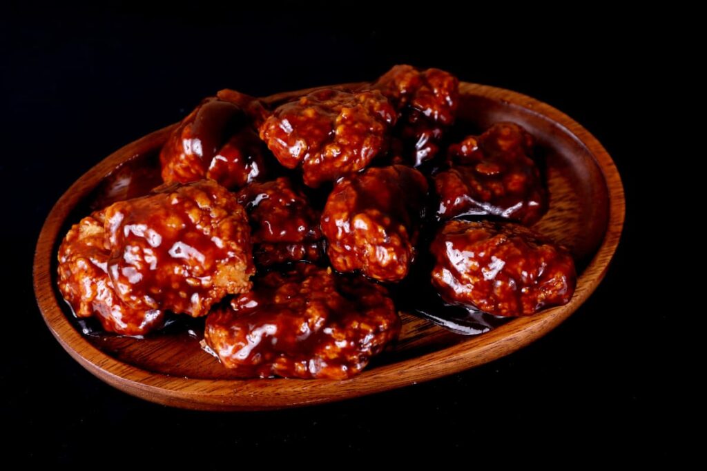 Chick-Fil-A Buffalo Sauce serves along with the chicken wings, these chicken wings serves in a brown color plate. These chicken wings are red in color and mixed with the Chick Fil A buffalo Sauce which is maroon red in color.