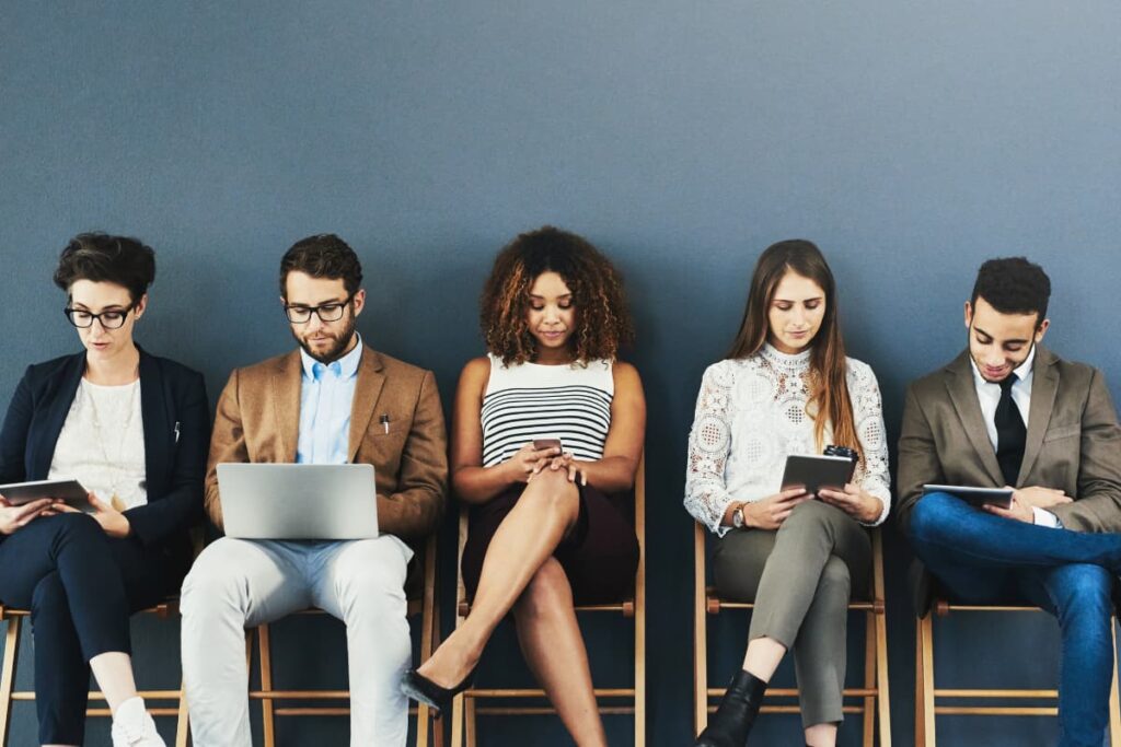 Lowe's Hiring Process is going on at the store and 5 people sat in the chairs having mobile, tab and laptop in hands came to attend the interview.