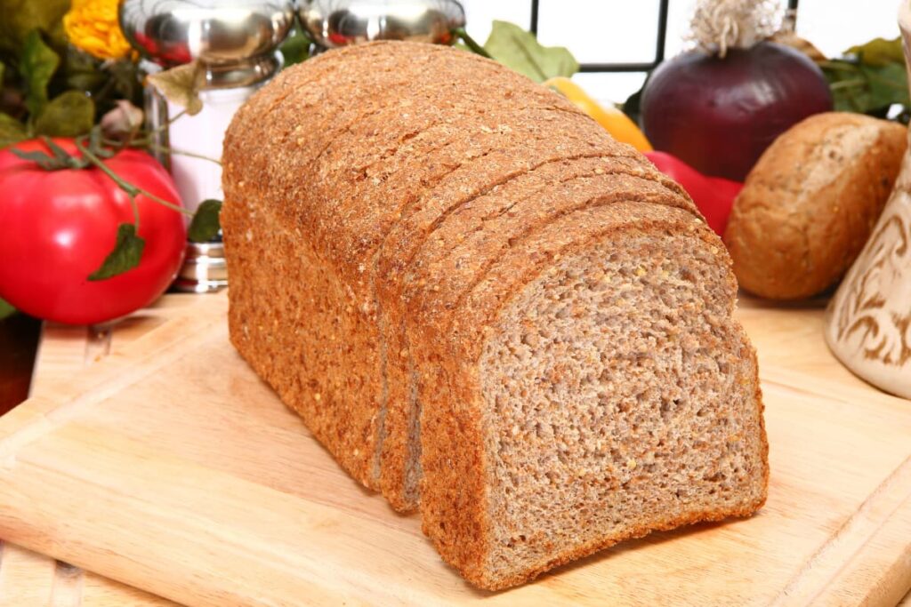 Bread From Walmart Bakery served with tomatoes, onions, salt and pepper on a wooden serving tray.