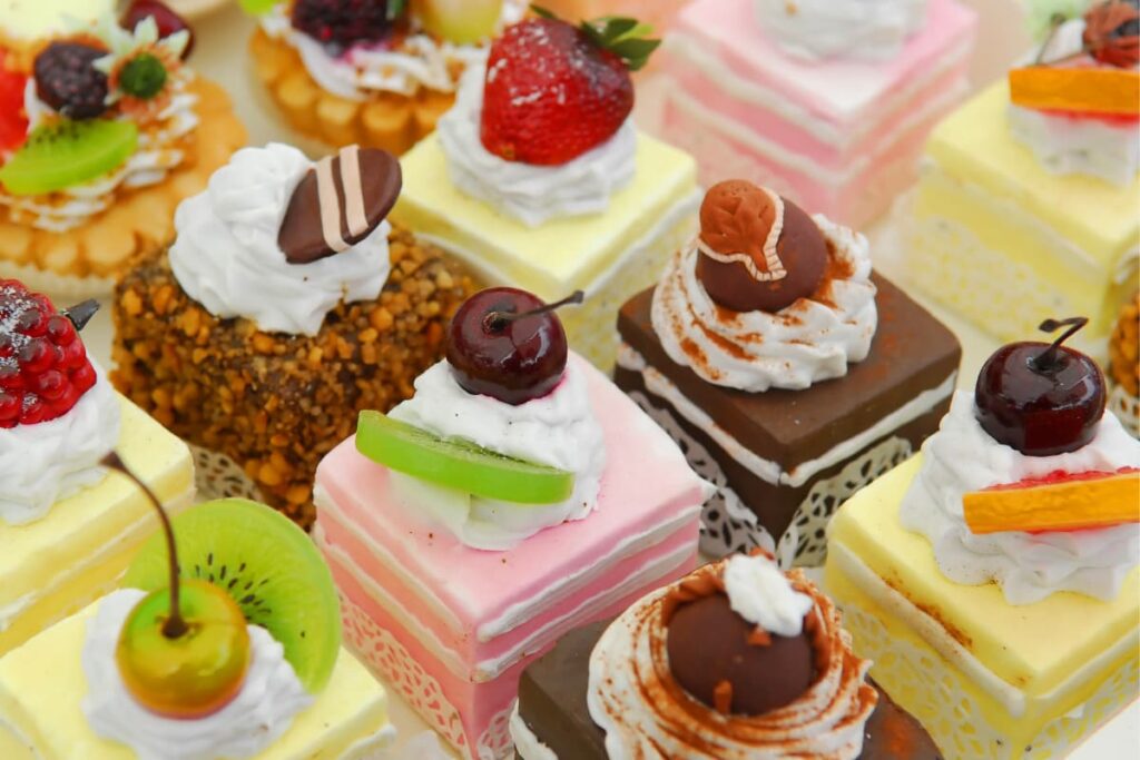 Walmart Cakes are served with various color frostings  like pink, yellow, brown along with strawberry, cherry, kiwi fruit slices.