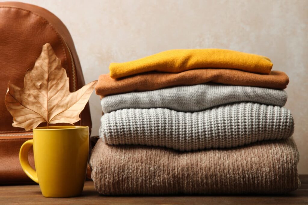 Walmart Clothes arranged one by one along with  mug, dried leaf and leather bag on a wooden table.