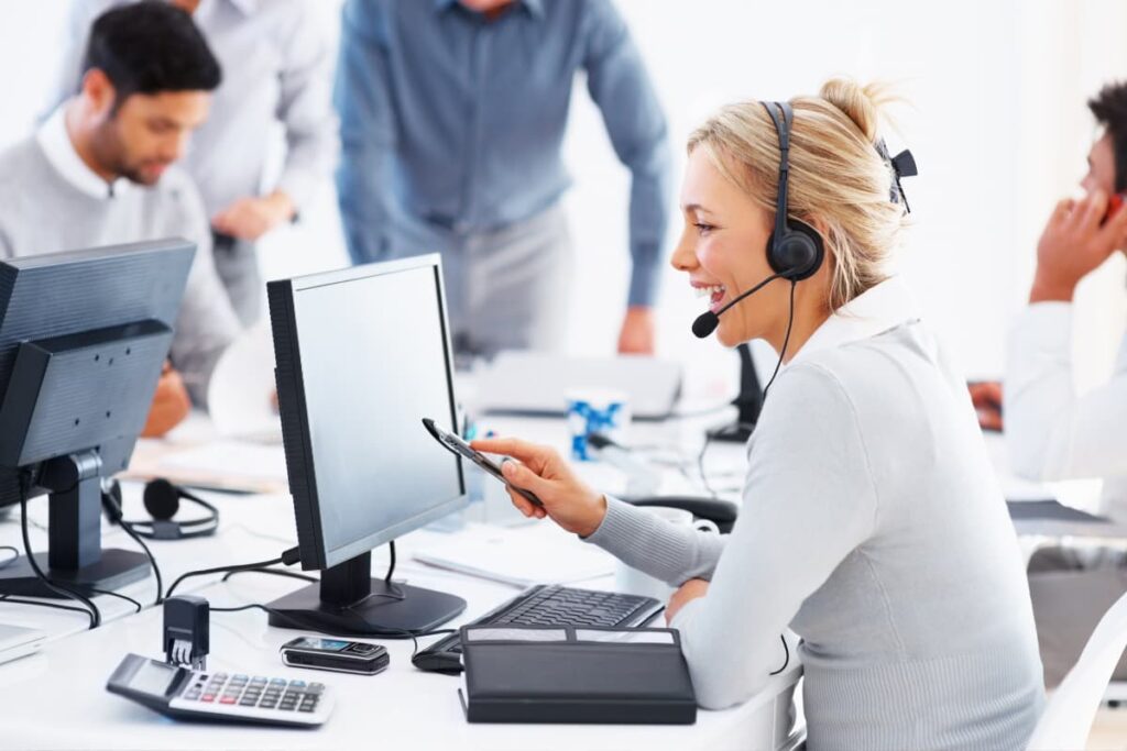 Walmart Customer Service employees four men and one women answering customers calls through landline phones in front of their desktops.