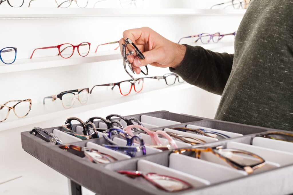 A person is checking Walmart Glasses in order to buy try different frames and colors of frames in a partition box.