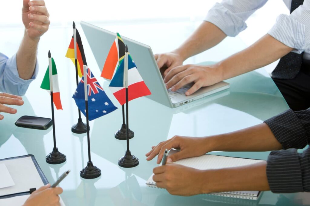 Walmart International Strategy discussed by three employees by using laptop, pens, files and international flags on a table.