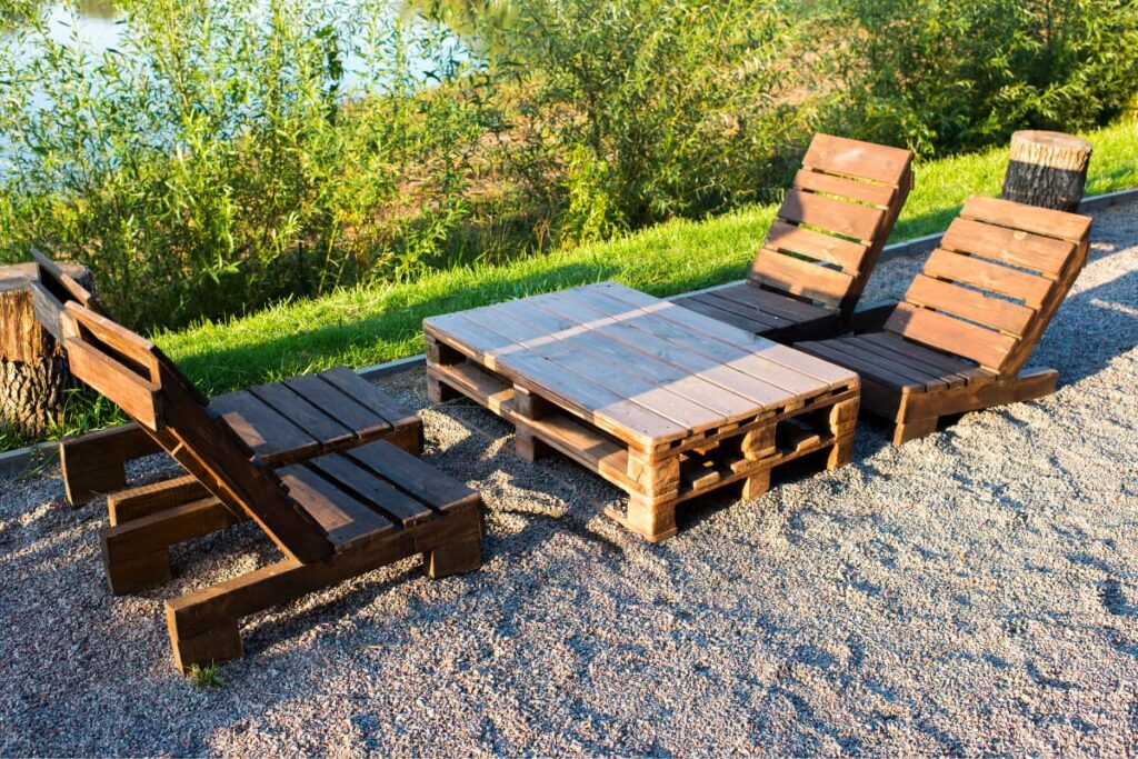  Walmart Pallets decorated as a center tab le along with two wooden chairs in a green garden.