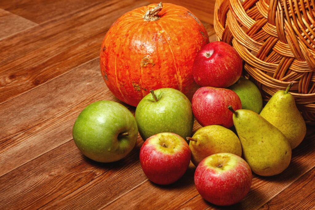 Walmart Pumpkin served with three green apples, four apples and three peers on a wooden table.