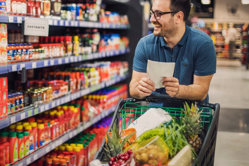 A man comparing Walmart Vs Target prices and products like fresh vegetables, sauces, fruits, food items while his shopping.