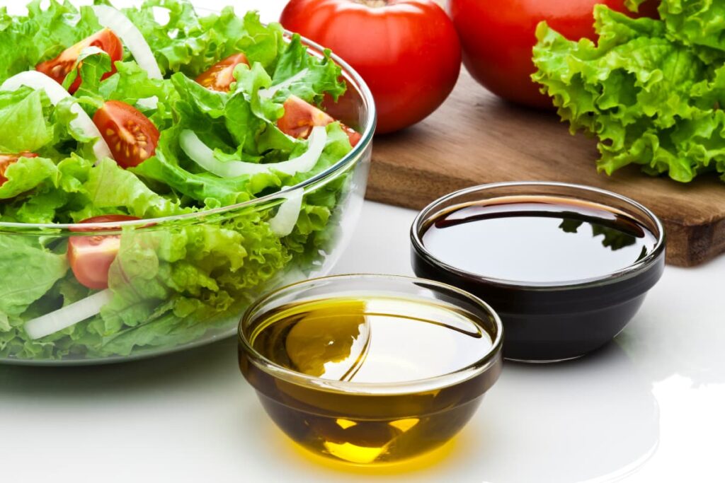 Chick-Fil-A Salad Dressings includes, 2 types of sauces (one is black in color, and the other is mustard yellow color), lettuce and 2 tomatoes. Chick-Fil-A Salad serves in a glass bowl, and it includes onion slices, tomato slices, and lettuce.