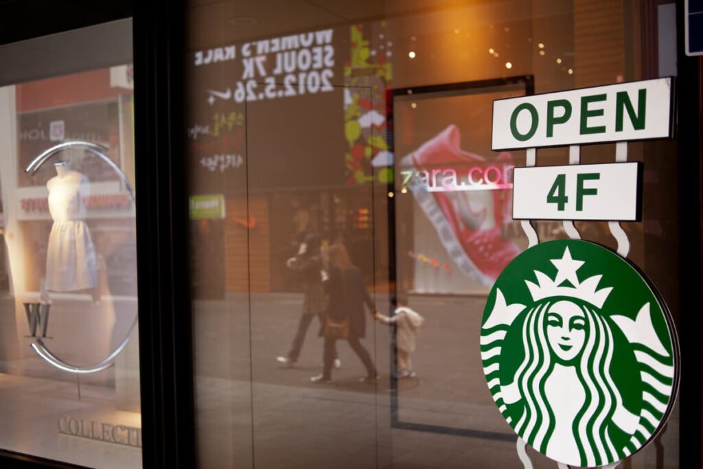 Starbucks Open mentioned on the before glass and above the starbucks logo. Starbucks open is mentioned in white and green color combination.