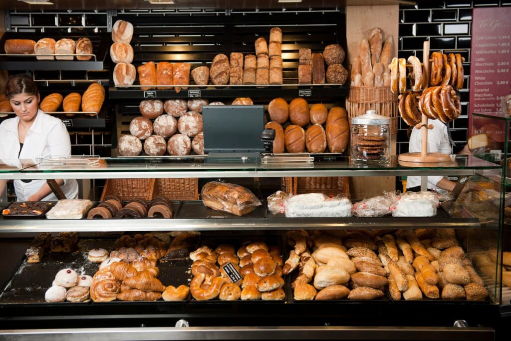 A baker in a Walmart Bakery which is having different types of breads, croissants, mini breads.