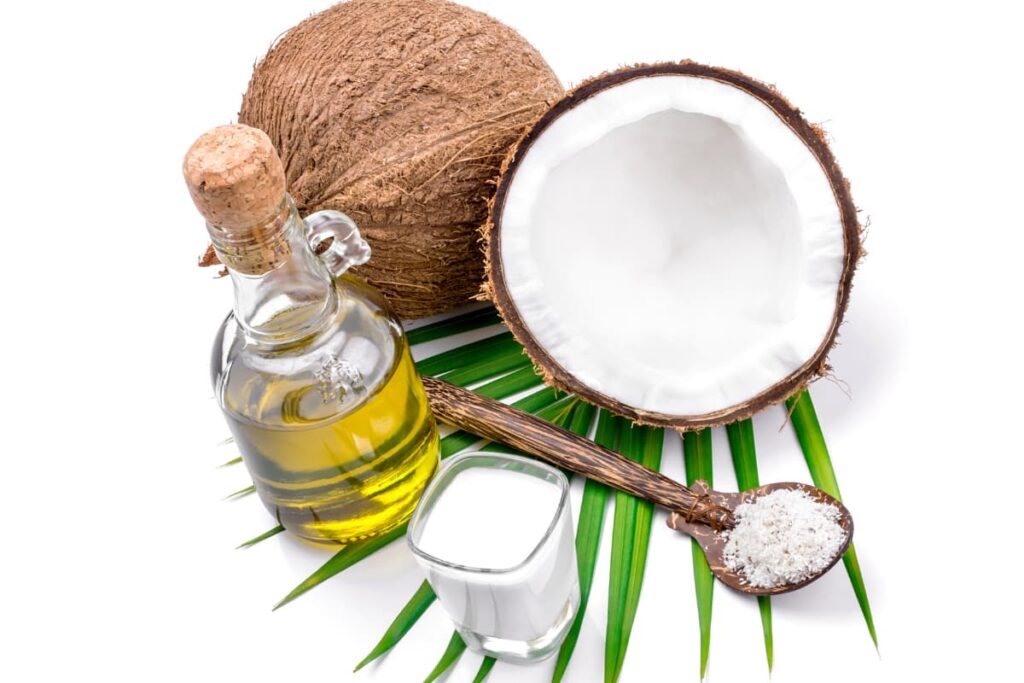 Coconut Oil In Walmart along with two pieces of Coconuts, one spoon of coconut powder, small glass of coconut milk and a bottle of coconut oil on a palm leaf.