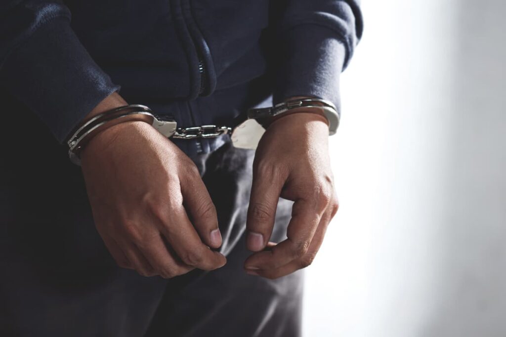 Felons Hiring At Publix Company interviewing a person who wears blue color prison  uniform and handcuffs.